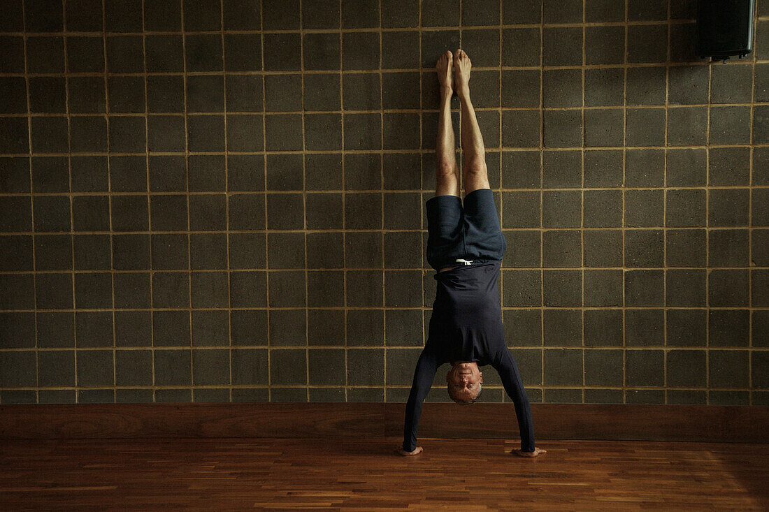 Älterer Mann, der Yoga übt, Handstand