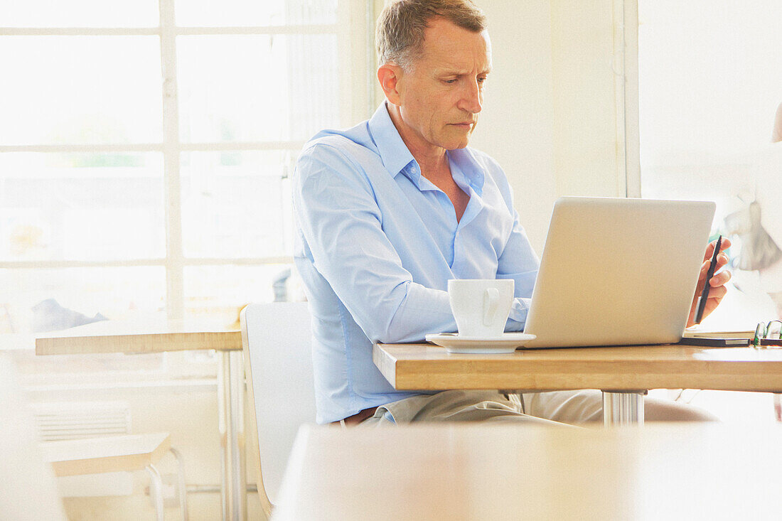 Mature Man Using Laptop in Cafe