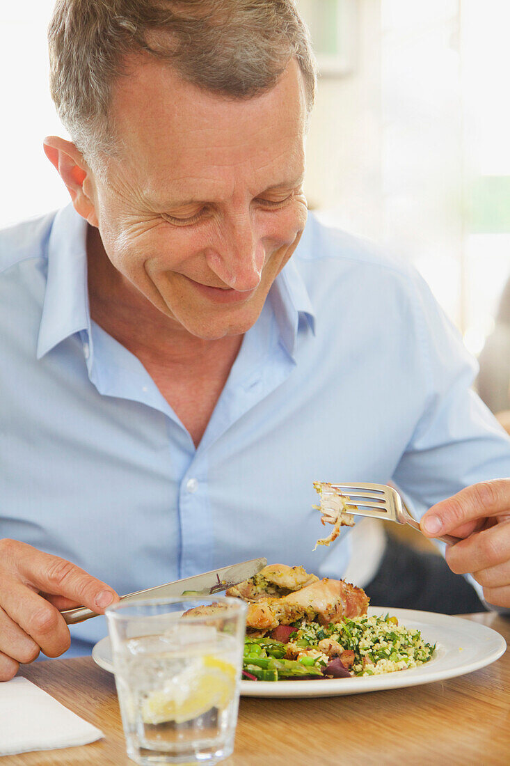 Mature Man Eating Lunch at Restaurant Smiling