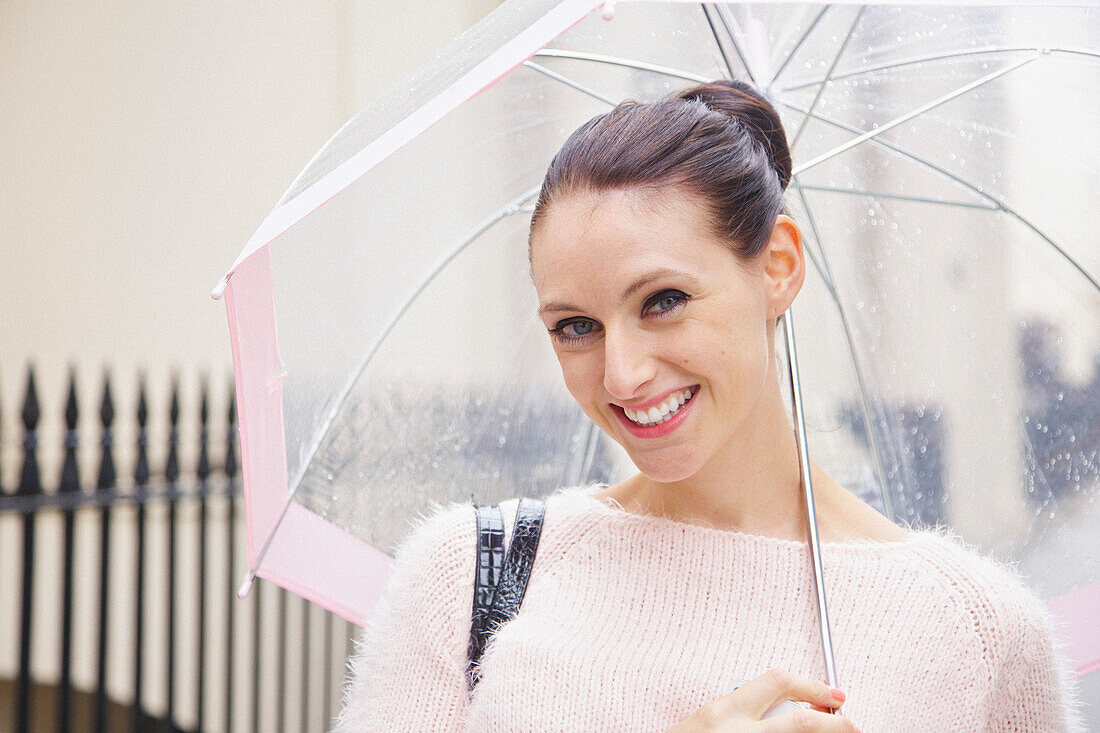 Smiling Woman Holding Umbrella in a London Street