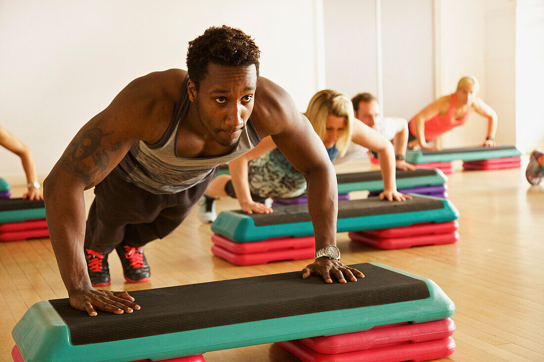 Mann macht Liegestütze beim Step-Aerobic-Kurs