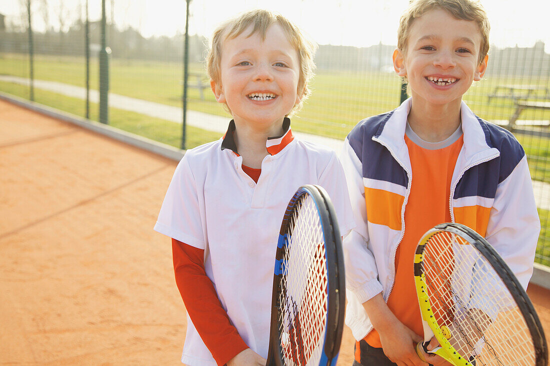 Two Young Boys Holding Tennis Rackets Smiling