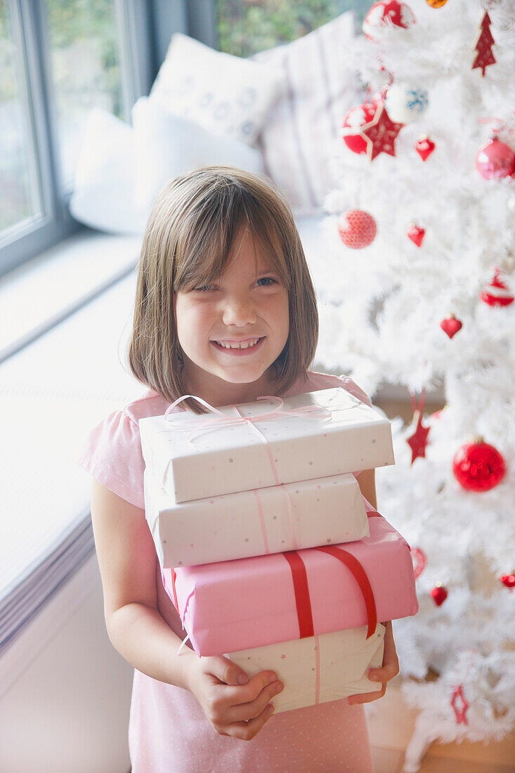 Smiling Young Girl Holding Stack of Christmas Presents