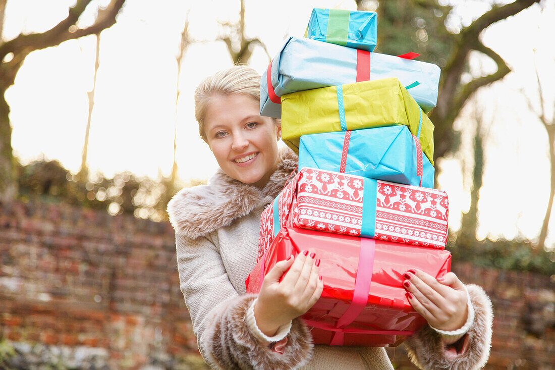 Junge Frau hält Stapel von Weihnachtsgeschenken im Freien