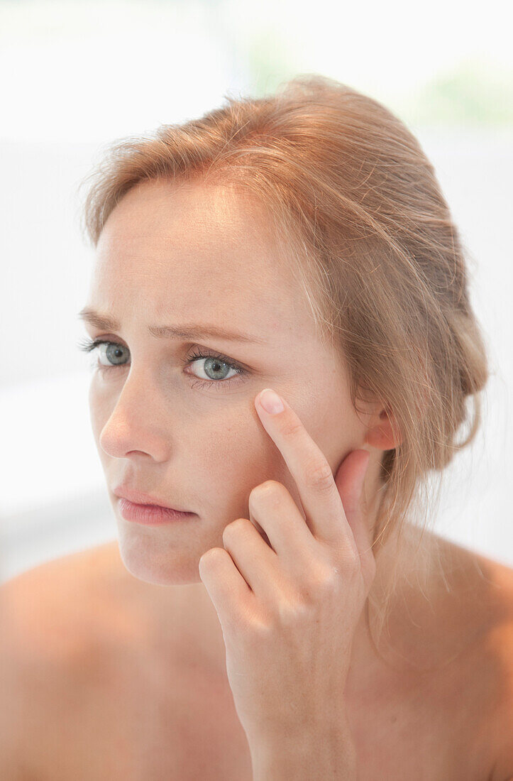 Concerned Woman Looking in Mirror Checking her Face