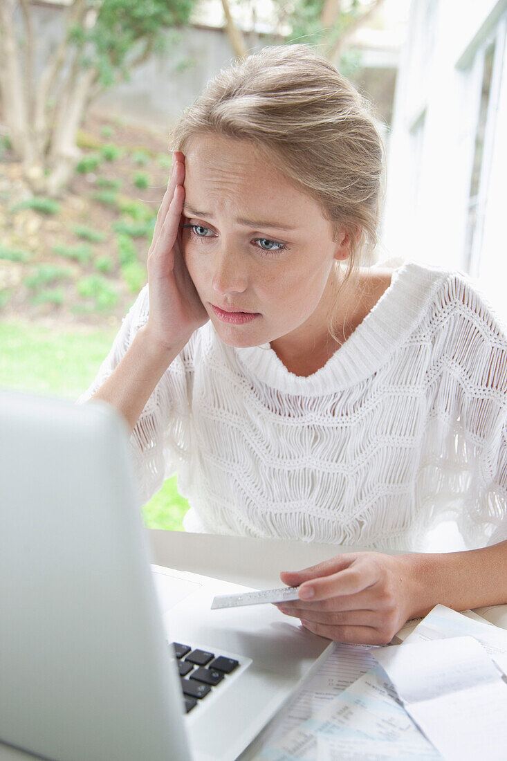 Upset Woman Holding Credit Card Looking at Laptop Screen