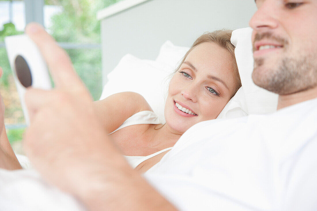 Ehepaar im Bett mit Smartphone