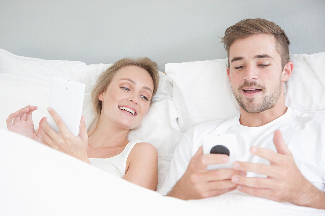 Ehepaar im Bett mit Smartphone