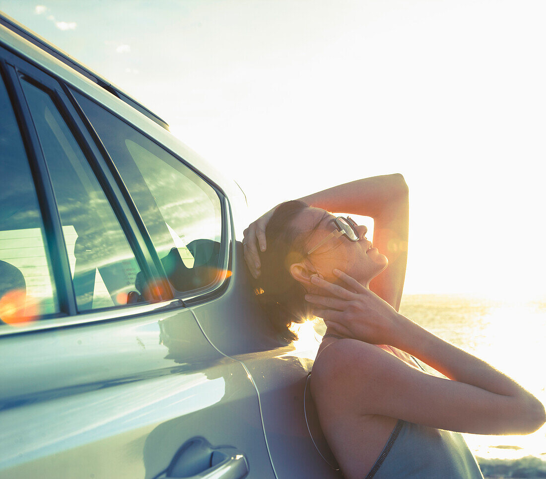 Woman Leaning against Car at Sunset