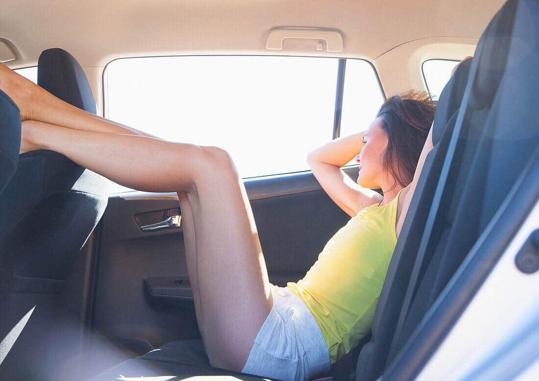 Woman Reclining in Car Back Seat with Legs Raised