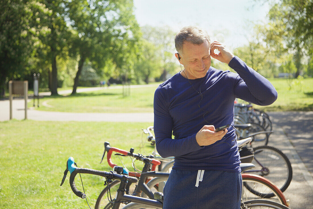 Älterer Mann im Park, der mit seinem Smartphone Musik hört