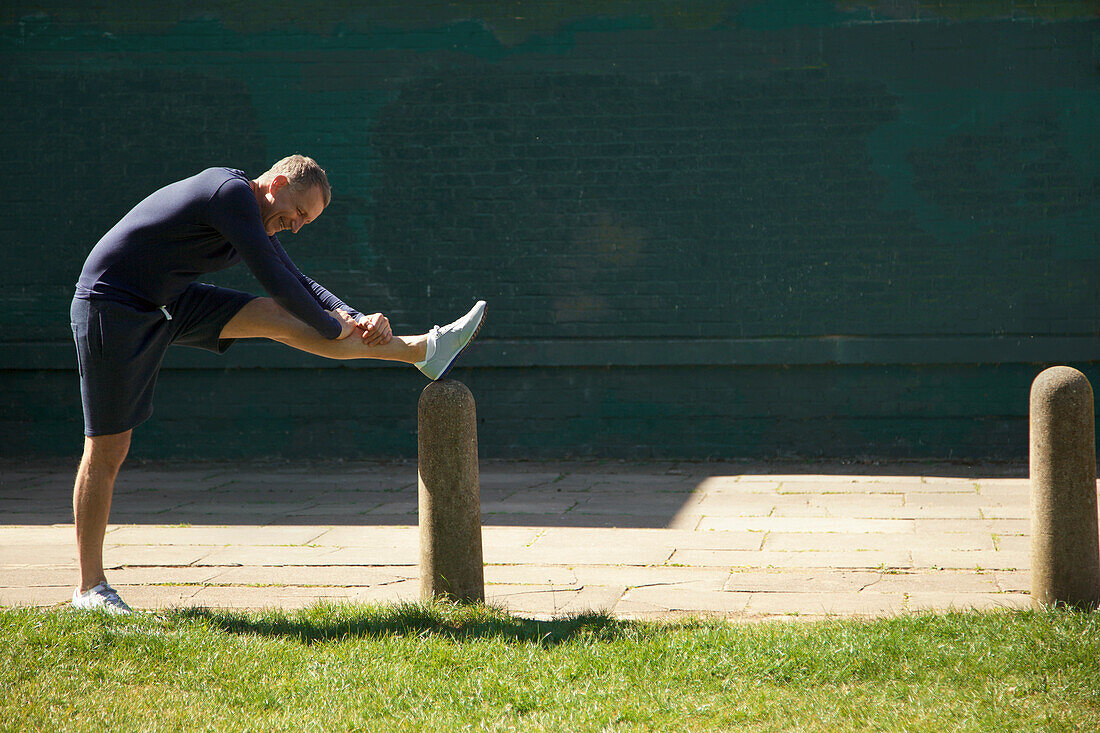 Älterer Mann streckt sein Bein im Park aus