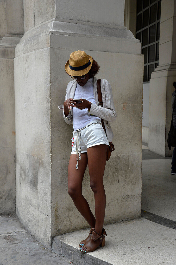 Cuba,La Havana,a young metis woman dressed in short  shorts is consulting her phone