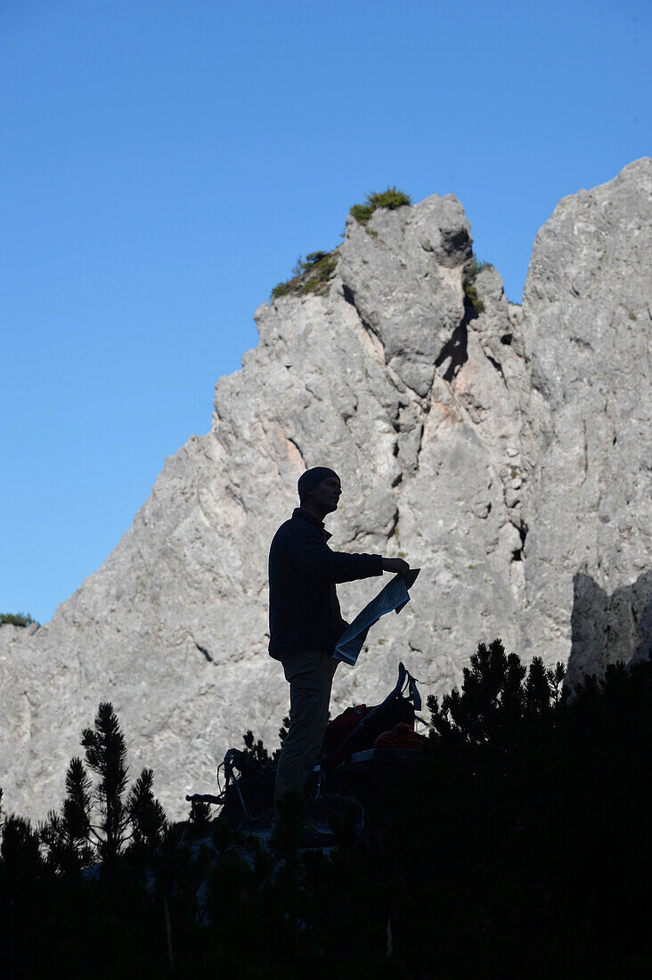 Österreich,Steiermark,ENNSTAL Alpen,Luchspfad,Silhouette eines Mannes, der eine Wanderkarte hält, die sich von einem klaren Berg abhebt