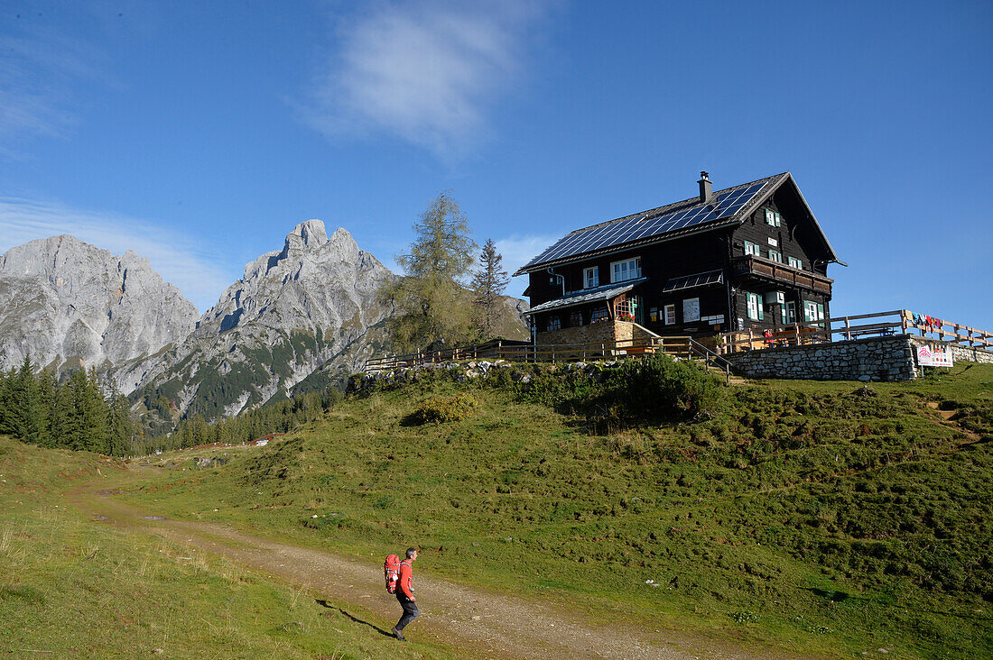 Austria,Styria,ENNSTAL Alps, a lonely man carrying a red backpack walks towards the Moedlinger mounatin hut above the small city of Admont.