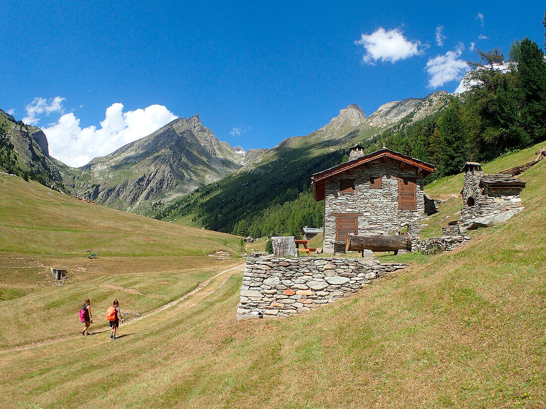 France,Alps,savoie,Vanoise national Park,2 persons are hikking on a mountain trail along a dry stone chalet in the OrgÃ¨re valley dominated bythe DORAN needle 3040m