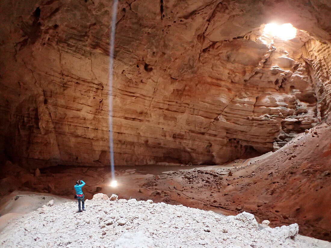 Sultanate of Oman,AS Sharqiyah region,Salma plateau,cave of Majlis Al Jinns,a man stands alone in the very bottom of the immense abyss of Majlis Al Jinns where daylight falls in a beam of light