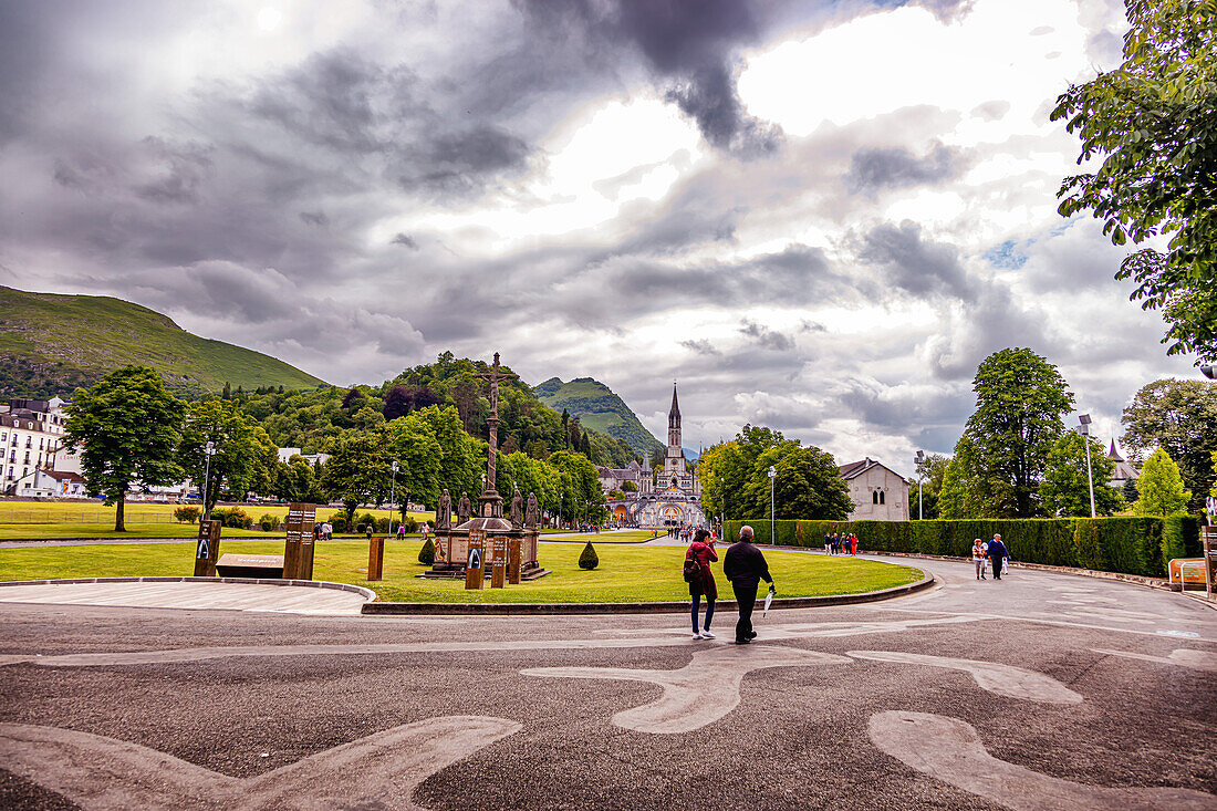 LOURDES - 15. JUNI 2019: Christliches Kreuz auf dem Hintergrund der Basilika Unserer Lieben Frau vom Rosenkranz in Lourdes,Frankreich