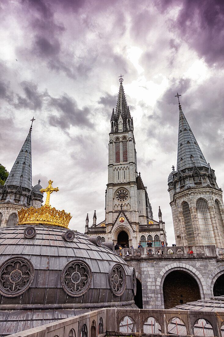 LOURDES - 15. JUNI 2019: Christliches Kreuz auf dem Hintergrund der Basilika Unserer Lieben Frau vom Rosenkranz in Lourdes,Frankreich