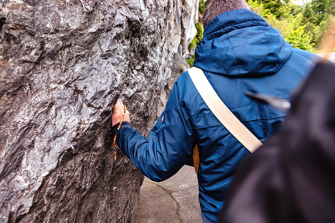 LOURDES - 15. JUNI 2019: Gläubige berühren den Stein der heiligen Grotte von Lourdes