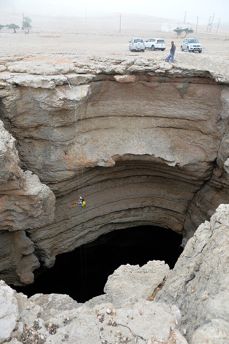 Sultanat Oman,AS Sharqiyah Region,Salma Plateau,Höhle von Majlis Al Jinns,ein Mann seilt sich in die gigantische Schlucht von Majlis Al Jinns ab