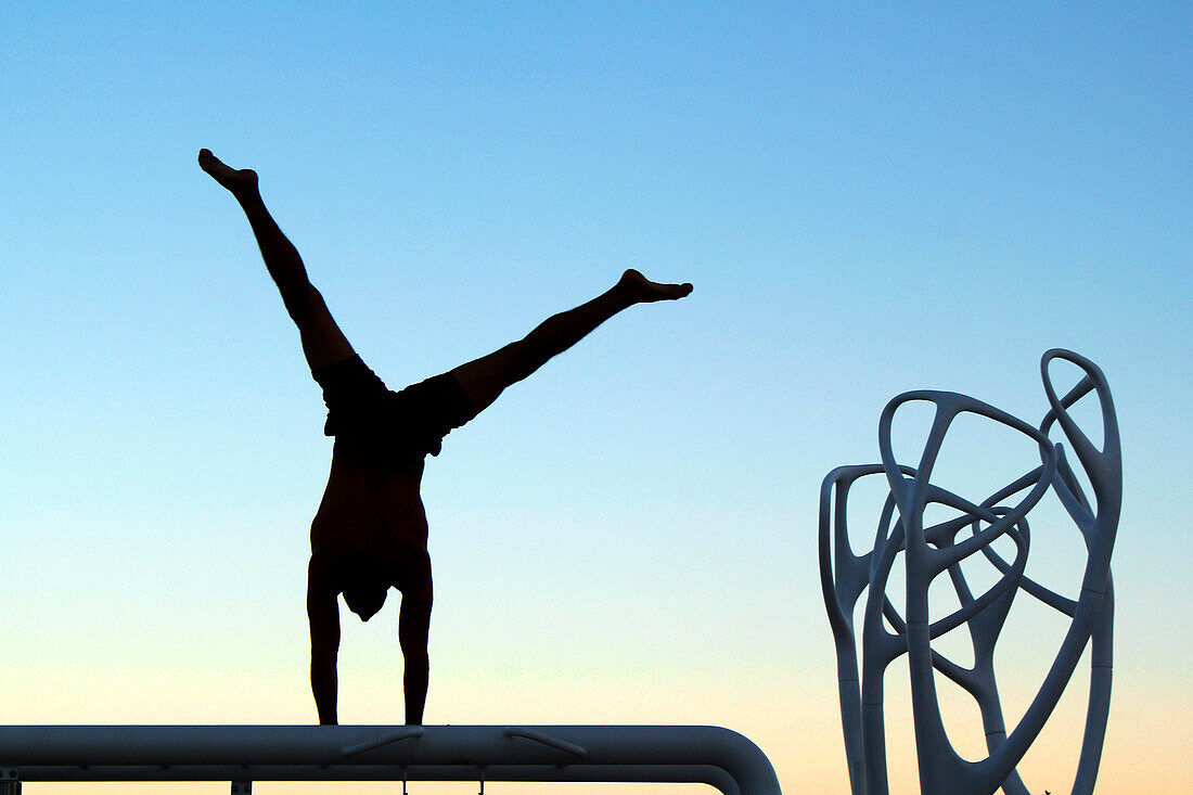 USA. Florida. Miami. Miami Beach. South Beach. Ocean Drive. Man practicing gymnastics at dusk.