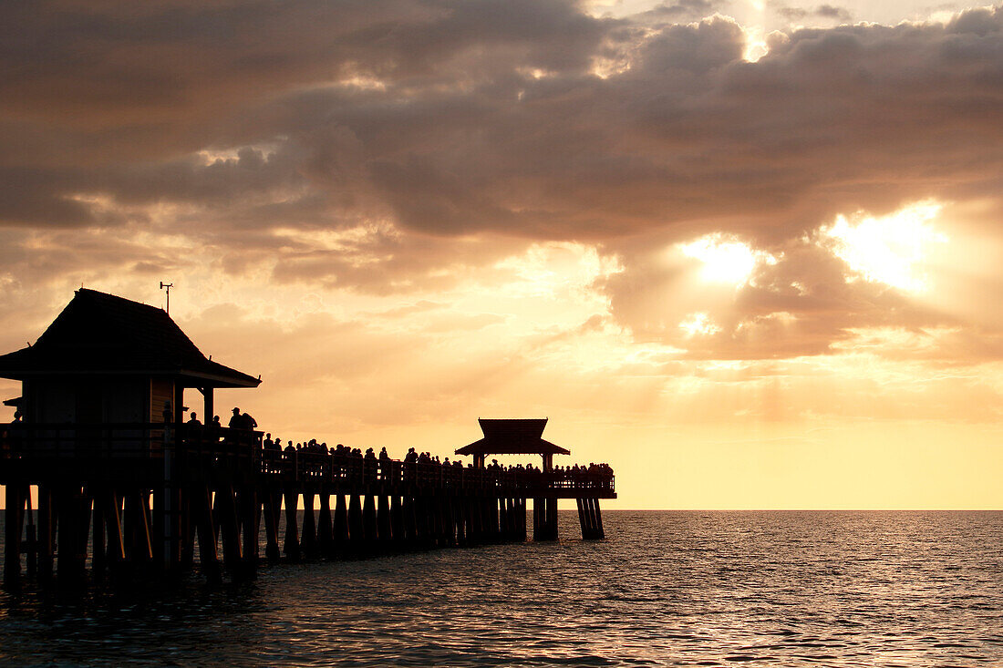 USA. Florida. Naples. The Pier. The beach. Sunset on the famous Pier. Tourists admiring the scene. Sailing ship.