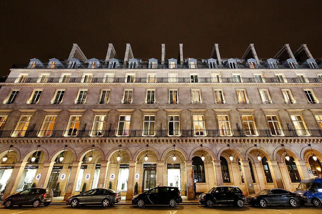 Paris. 1. Bezirk. Der Tuileriengarten bei Nacht. Rivoli-Straße. Gebäudefassaden mit darunter geparkten Autos.