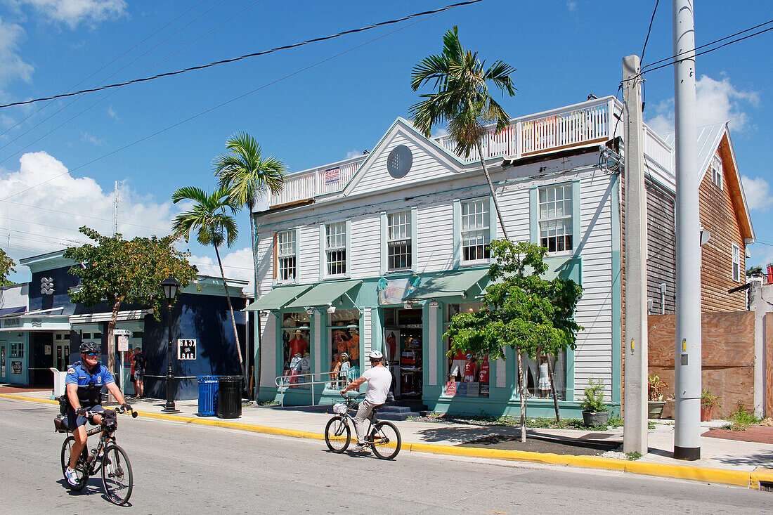 USA. Florida. Die Keys. Key West. Historisches und touristisches Zentrum. Tourist und Polizist auf dem Fahrrad.