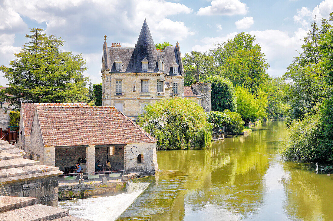 France. Seine et Marne. Medieval village of Moret sur Loing. Tourists picnicking in the foreground.