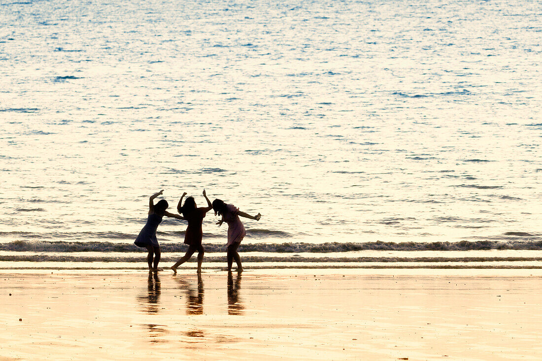 France. Normandy. Department of Manche. Granville region. Teenage girls dancing on the beach at high tide.