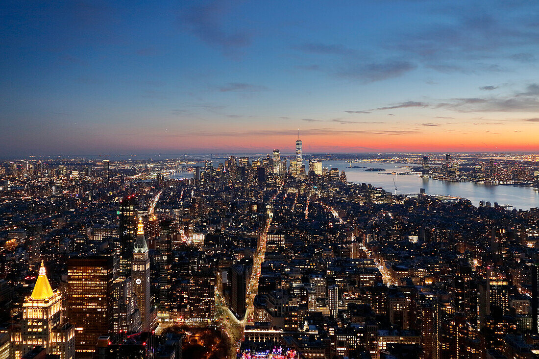 USA. New York City. Manhattan. Empire State Building. Blick von der Spitze des Gebäudes in der Abenddämmerung und bei Nacht. Blick auf das One World Trade Center und die Unterstadt. Der Hudson River ist rechts zu sehen.