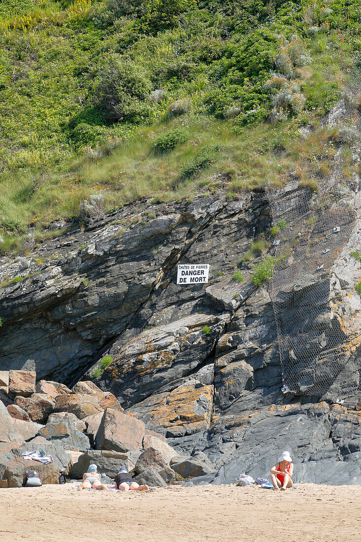 Frankreich. Normandie. Departement Manche. Granville im Sommer. Blick auf die Küste und einen Teil des Strandes. Gefährliche Felsen durch herabfallende Steine und Felsen. Schild „Lebensgefahr“.