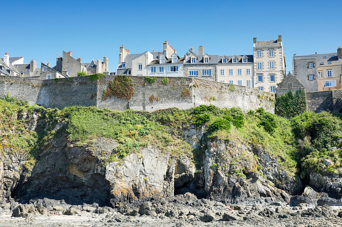 France. Normandy. Department of Manche. Granville during the summer. View from the coast at ebb tide. Tourists sunbathing.