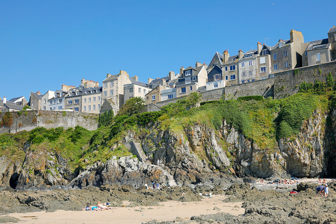 France. Normandy. Department of Manche. Granville during the summer. View from the coast at ebb tide. Tourists sunbathing.