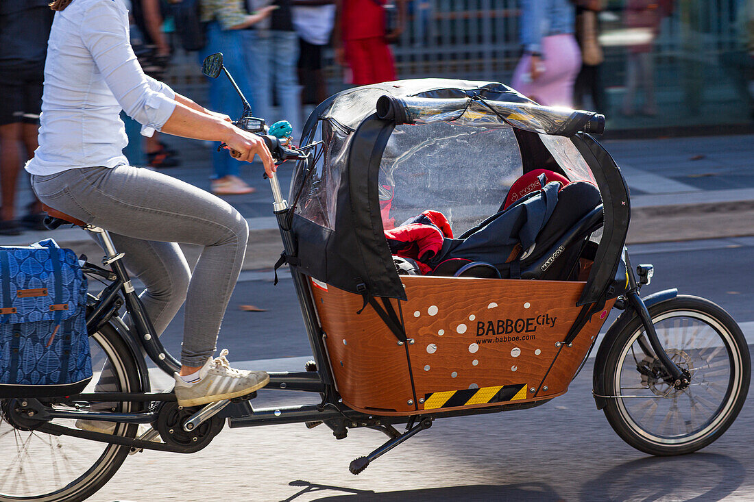 France,Nantes,44,Cours des 50 Otages,bicycle traffic. A mother riding an electric cargo bike,June 2021.