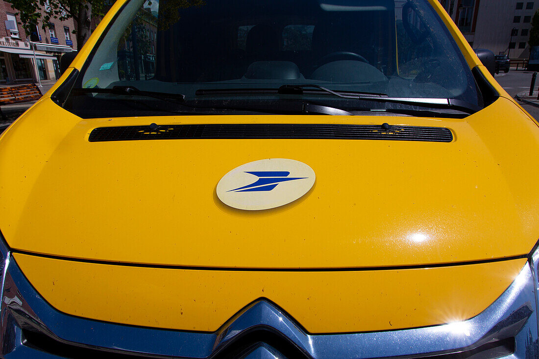 Gelbes Postfahrzeug mit dem Logo auf der Motorhaube