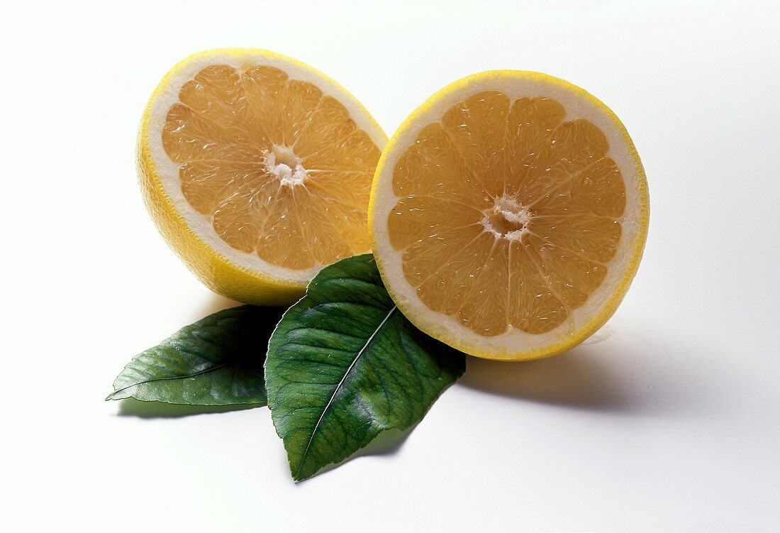 Two halves of a yellow grapefruit & two leaves