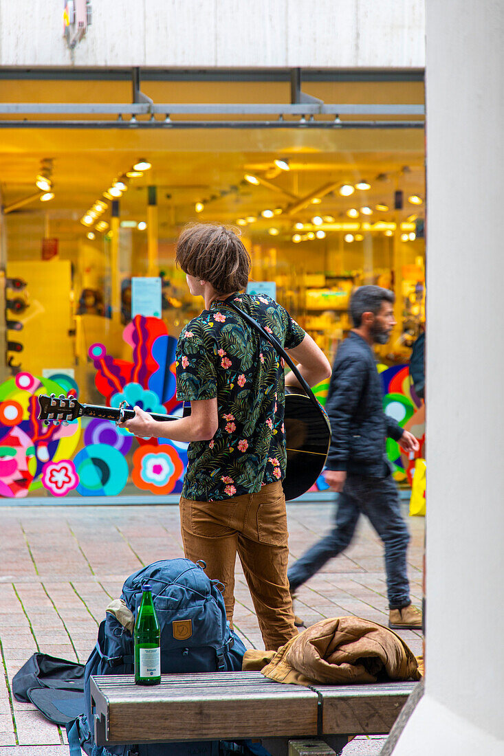 Young person playing music in a pedestrian street.