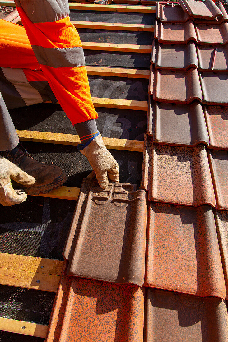 Worker installing tiles on a roof