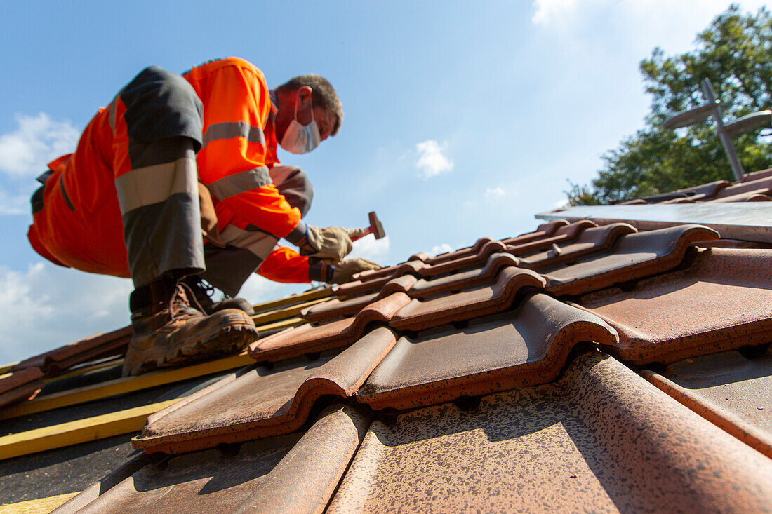 Worker installing tiles on a roof