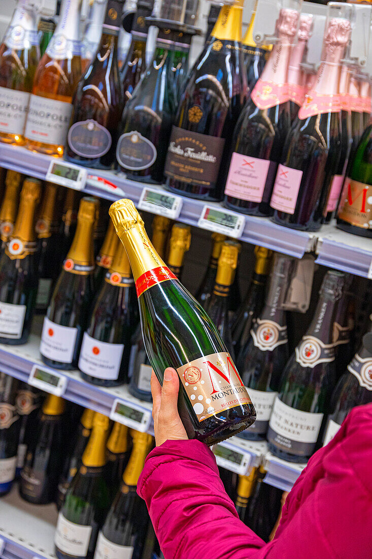 Blonde Frau beim Einkaufen im Supermarkt während einer Weinmesse. Champagner Moët et Chandon