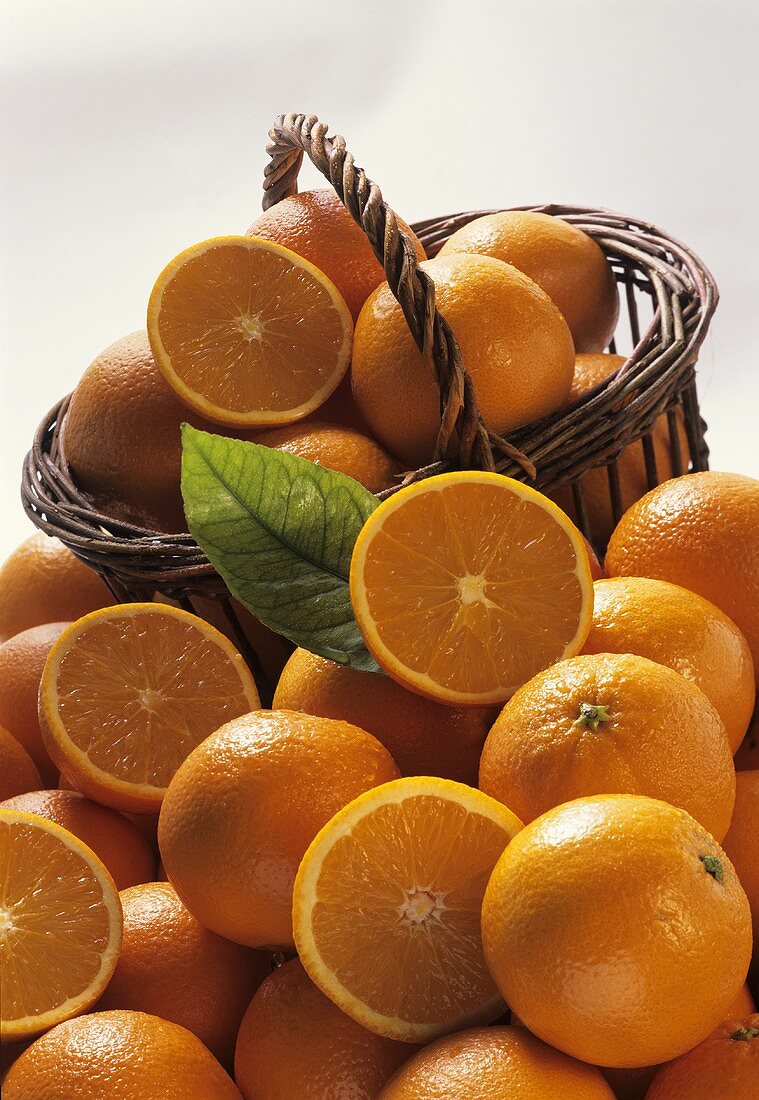Korb voll Orangen vor vielen Orangen & Orangenhälften