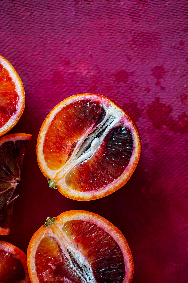 Sliced blood oranges on a pink background