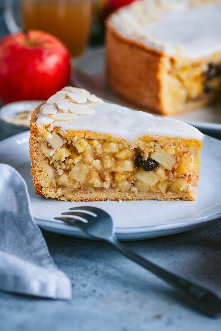 Gedeckter Apfelkuchen mit Zuckerglasur und Mandeln