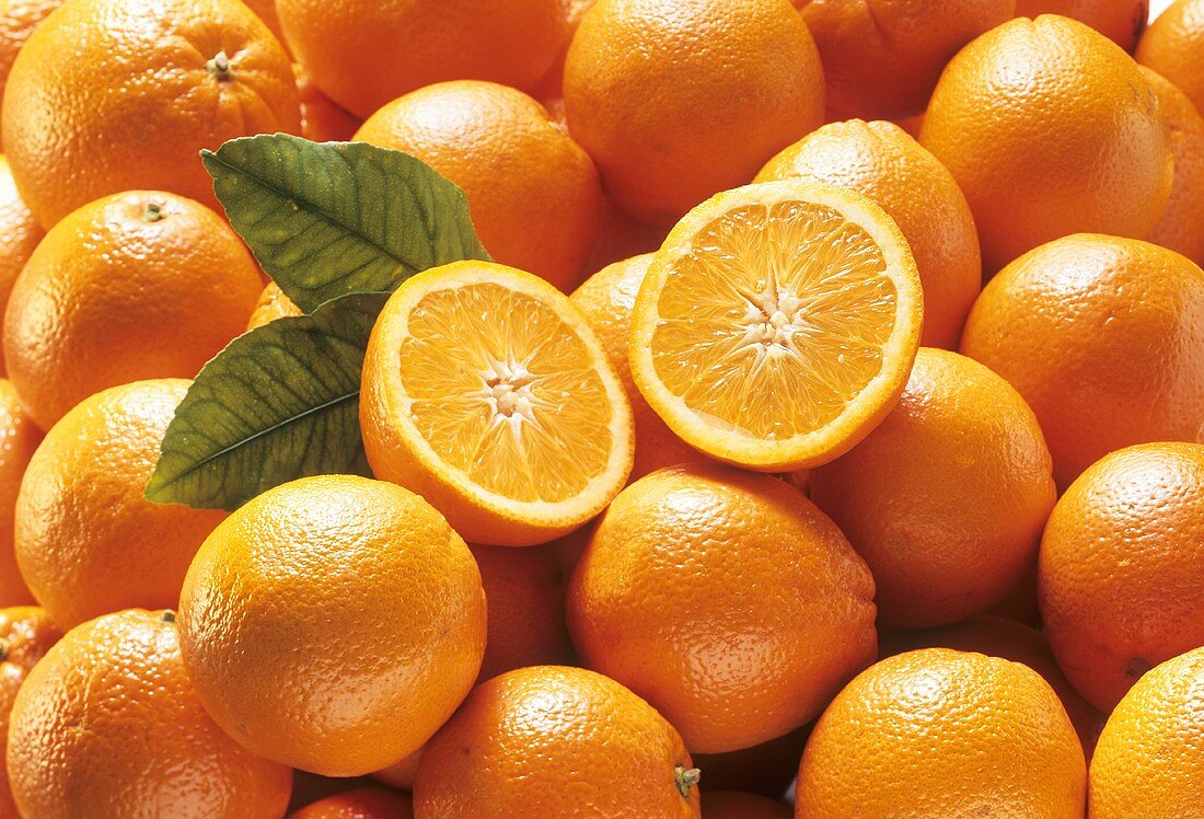 Oranges, one halved on top (close-up)