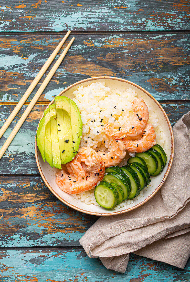 Poke bowl with rice, prawns, avocado and cucumber