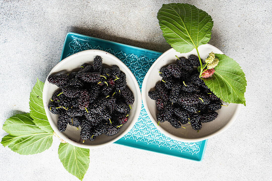 Mulberries with leaves in small bowls