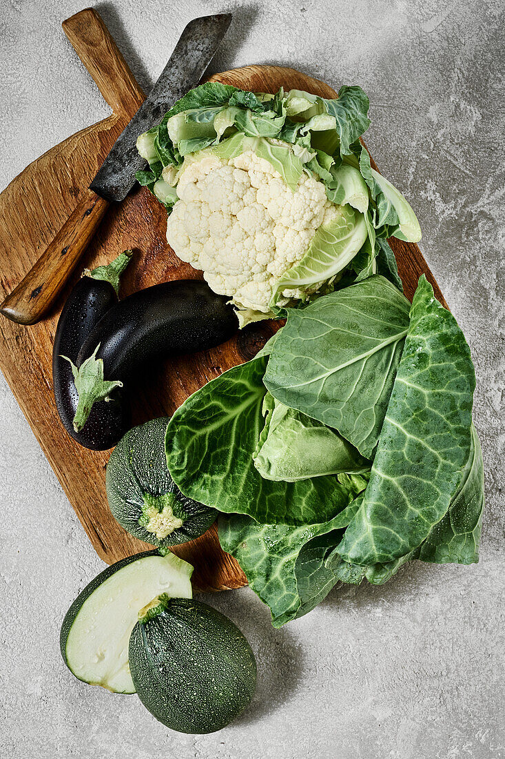 Aubergines, cauliflower, courgettes and pointed cabbage on a wooden board