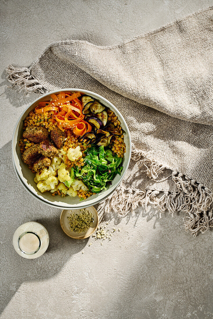 Bowl mit herbstlichem Gemüse, roten Linsen und Falafel